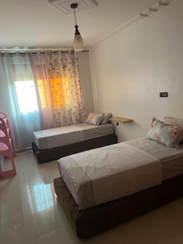 a bedroom with two beds and a window at Appartement proche toutes commodités in Berkane