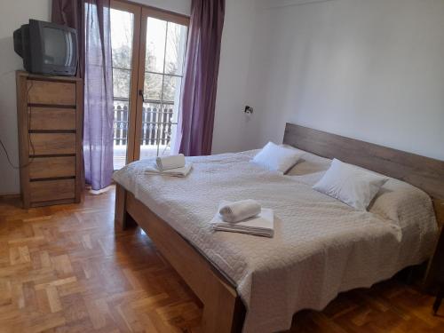 a bedroom with a bed with two towels and a tv at Peregrino Vendégház in Budaörs