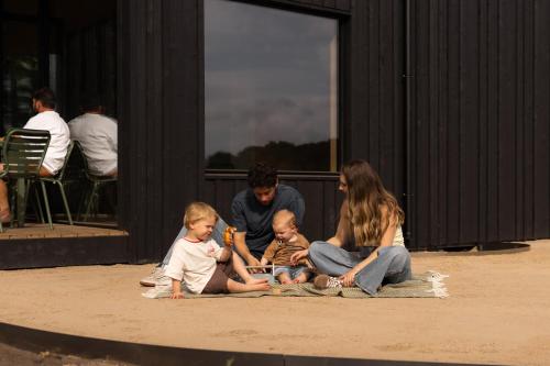 a family sitting on the ground in front of a building at Eco by Nature - De Adem - in Heythuysen