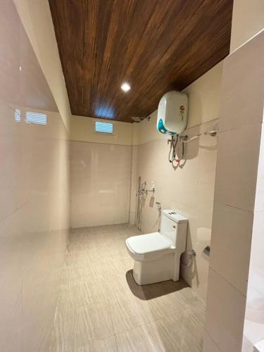 a bathroom with a toilet with a wooden ceiling at The Hillshade villa in Borpāni