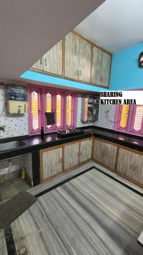 an empty room with aitating kitchen area with pink windows at Shree niwas- Blue Room in Bokāro