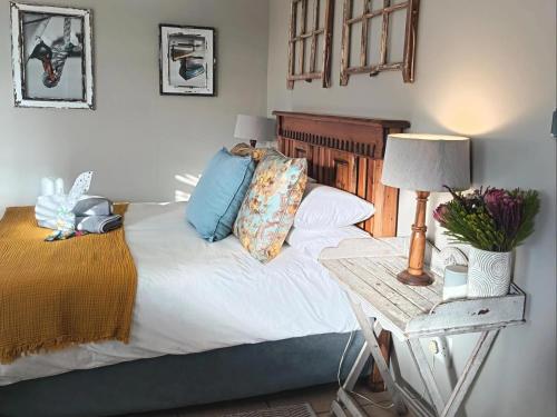 a bed with pillows and a table with a lamp at Nouvelle Vie Self-catering Accommodation in Reebok