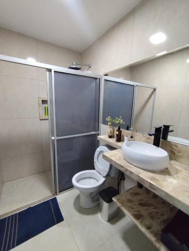 a bathroom with a shower and a toilet and a sink at Dunas House in Luis Correia