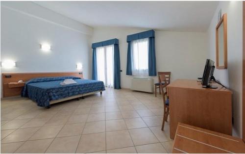 a bedroom with a bed and a desk with a television at Hotel Isola Rossa in Bosa
