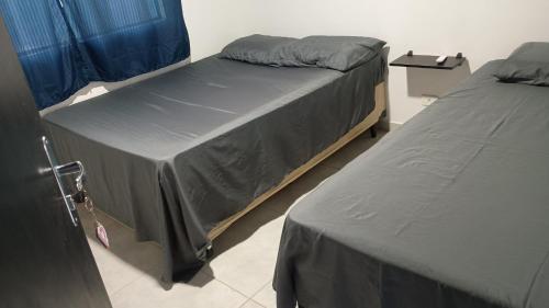 two twin beds in a room with blue curtains at Cantinho,RMA in Bom Jesus dos Perdões