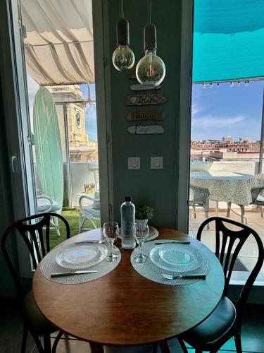 a wooden table with two plates and wine glasses at Les Terrasses, charme et authenticité en Hyper Centre de TOULON, Idéal pour un séjour romantique ou une escapade urbaine in Toulon