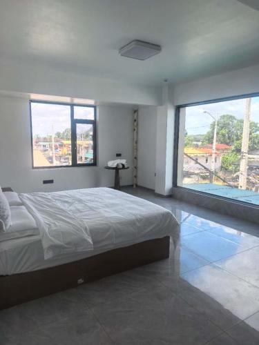 a bedroom with a bed and two large windows at #1 Diamond Hotel and Residences in Georgetown