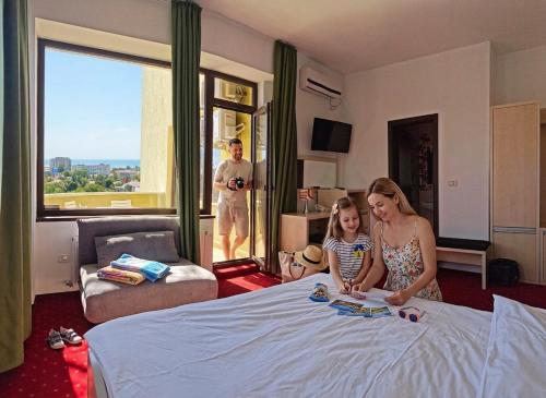 a woman and a little girl sitting on a bed at Alma by iVAVev in Mamaia