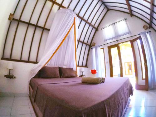 a bedroom with a bed with a mosquito net at Gili Air Santay 2 in Gili Islands