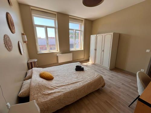 a small bedroom with a bed and two windows at Charme et confort - Maison Roubaix 5 chambres in Roubaix