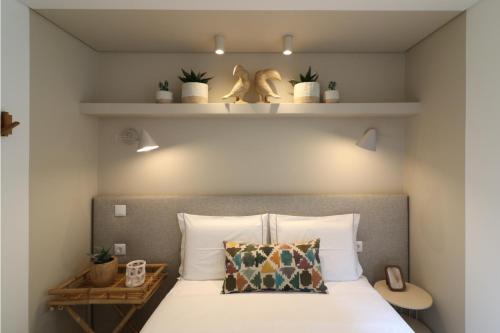 a bedroom with a bed with plants and shelves at Tinico's Guest Rooms in Nazaré