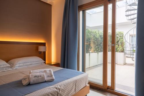 a bedroom with a bed and a large glass window at Hotel Scoglio Degli Achei in Torre Santa Sabina