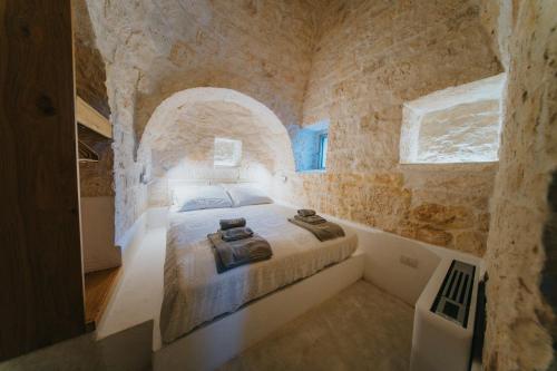 ein Schlafzimmer mit einem Bett in einem von Steinmauern umgebenen Raum in der Unterkunft Trullo Cervillo in Cisternino