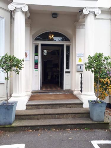 an entrance to a white building with columns and stairs at Episode Hotel in Leamington Spa