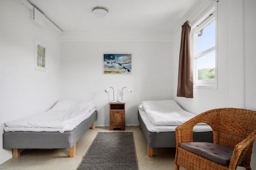 a room with two beds and a chair and a window at Hillesgården in Boarp