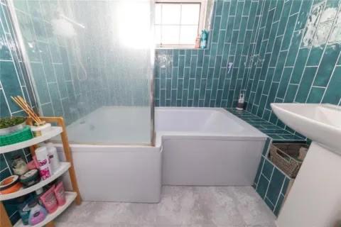 a green tiled bathroom with a tub and a sink at Entire 3 bedroom house in Luton
