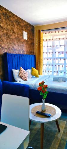a room with two beds and a blue couch and a table at Aheri Homes in Ruaka