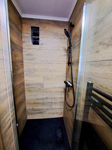 a shower in a room with a wooden wall at Chambre privée dans une maison d'hote in Liège