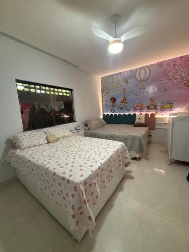 a bedroom with two beds and a wall with a mural at Casa 108 in Guaibim
