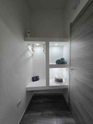 a hallway with a white wall with a shelf and a door at Isabel House in Capoterra