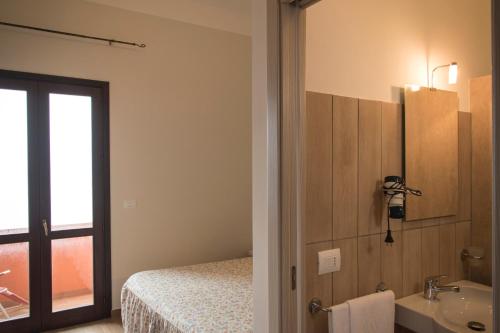 a room with a bathroom with a bed and a sink at Hotel Bue Marino in Pantelleria