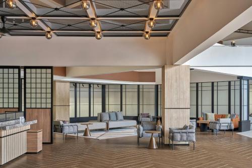 a lobby with chairs and tables and windows at Four Points by Sheraton Johor Bahru in Kampong Telok Jawa