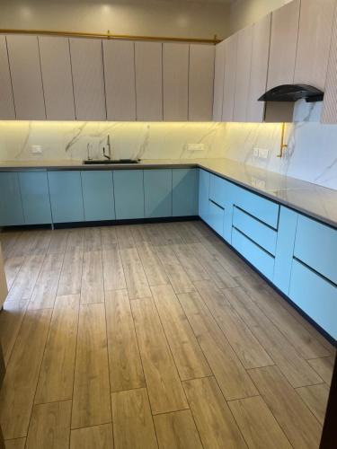an empty kitchen with blue cabinets and a wooden floor at Luxury Executive Homestay in Jāmb