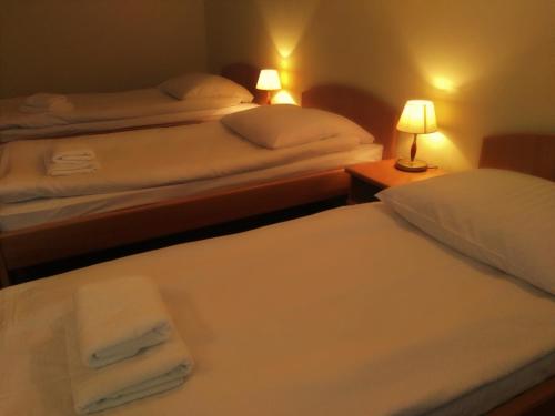 two beds in a hotel room with white sheets and towels at Hotel Bartis in Bartoszyce