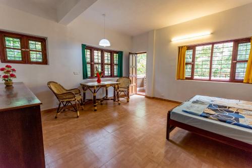 a living room with a table and chairs and a bed at BASIS Mountain House in Thekkady