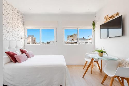 a white bedroom with a bed and a table at New Central Studio Torremolinos in Torremolinos