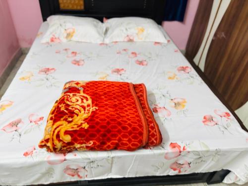 a red blanket on a bed with flowers on it at Lara Homestay duplex 1bhk in Secunderabad