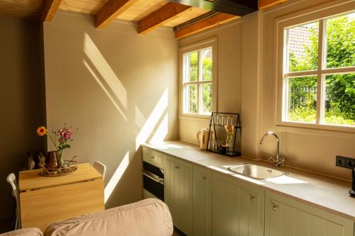 a kitchen with a sink and two windows at B&B by lin in Dodewaard