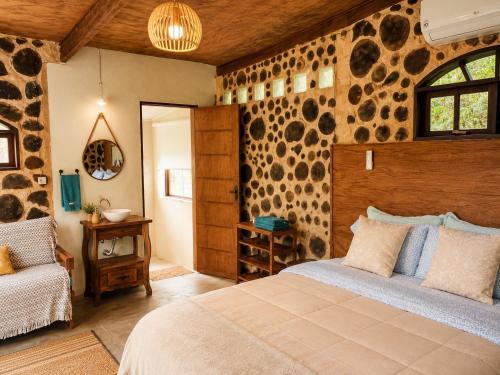 a bedroom with a bed in a room with stone walls at Jardim Mirim in Cananéia
