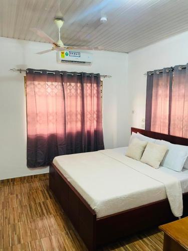 a bedroom with a large bed with red curtains at Joyet Guest House in Amasaman