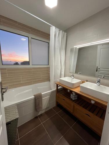 a bathroom with two sinks and a tub and a mirror at Villa Inelda in Saint-Paul