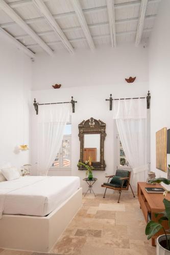 a white bedroom with a bed and a mirror at Allium Art House Symi in Symi