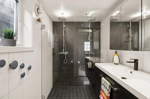 a bathroom with a shower and a sink and a mirror at Vinkelgata 20 Guesthouse in Stavanger