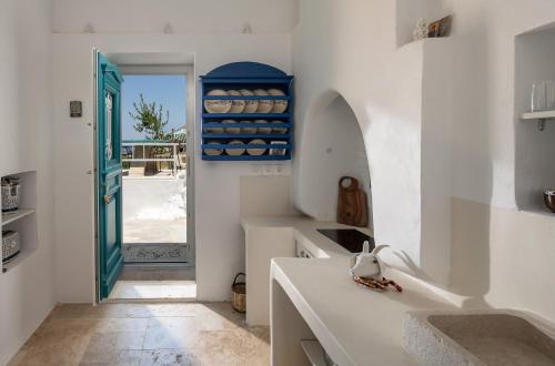 a kitchen with white walls and a blue door at Allium Art House Symi in Symi