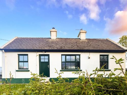 a white house with black windows and a green door at The Tailor's Cottage in Lahinch