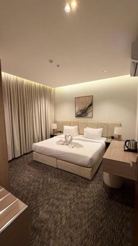 a bedroom with a large white bed and a desk at فندق لوسكا in Abha