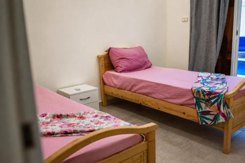 a bedroom with two beds with pink sheets at Villas avec piscine in Taguermess