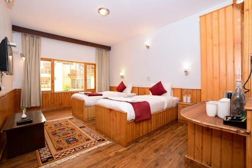 a hotel room with two beds and a television at Hotel Karakoram in Leh