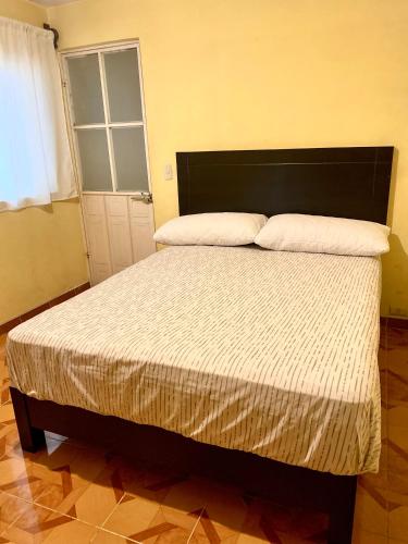 a bedroom with a large bed with white sheets at Accommodation near downtown in San Cristóbal de Las Casas