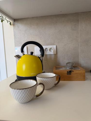 a yellow tea kettle and two cups on a counter at Tivat Cozy Studio in Tivat