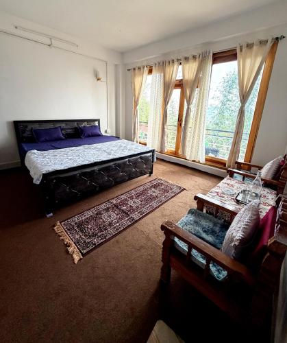 a bedroom with a bed and a couch and windows at Kepchaki Stay in Takdāh
