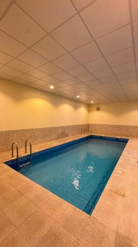 a large indoor swimming pool with blue water at فيلا هابي نايت in Ash Shafa