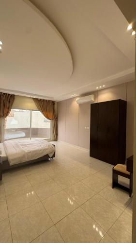 a bedroom with a bed and a large window at فيلا هابي نايت in Ash Shafa