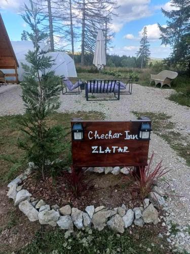 a sign in a park with a bench and an umbrella at Chechar Inn Zlatar in Nova Varoš