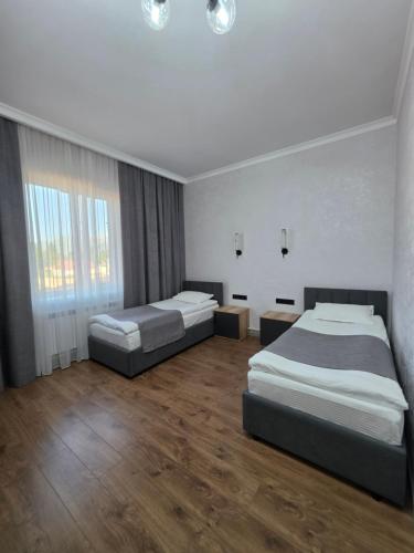 two beds in a hotel room with wood floors at TOI AT-BASHY HOTEl in At-Bashy
