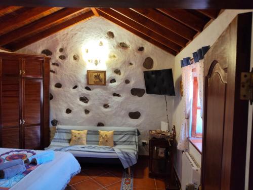 a bedroom with a rock wall with a couch at Casita Roque Nublo in Tejeda